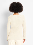 Back view of a cream waffle-knit sweater with subtle shimmer. Long-sleeved with ribbed cuffs and hem. V-neck not visible.