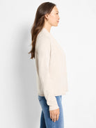 Light beige, fine-knit, open-front cardigan with long sleeves, shown on a woman from the side.