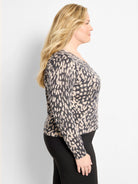 Beige pullover sweater with irregular dark grey speckled pattern and long sleeves, worn by a model.