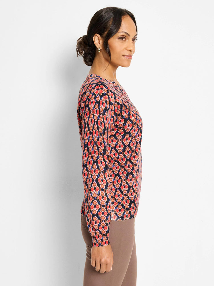 Long-sleeve sweater with an ikat pattern in red, orange, pink, blue, and brown on a dark background.