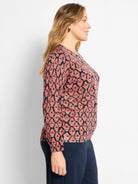 Dark navy sweater with red, orange, and blue ikat diamond pattern. Round neck, long sleeves.