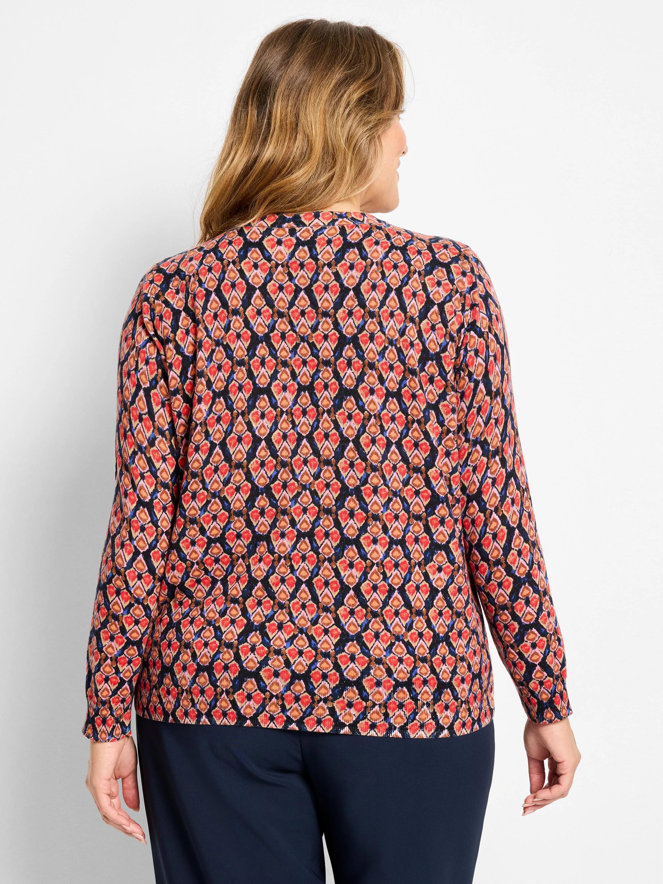 Dark navy sweater with a geometric ikat pattern in red, orange, brown, and blue diamond shapes. Back view.