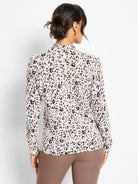 Back view of a cream mock-neck sweater with black, brown, and blue cheetah print spots.