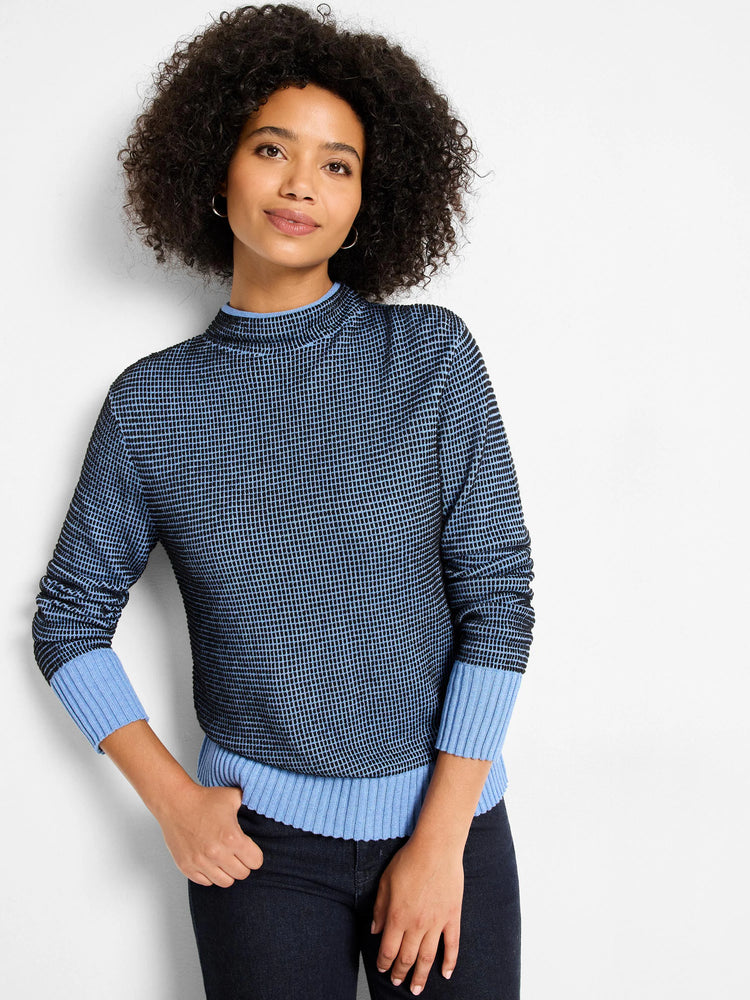 Funnel neck sweater in dark blue and light blue pixel knit. Features ribbed light blue cuffs and hem.