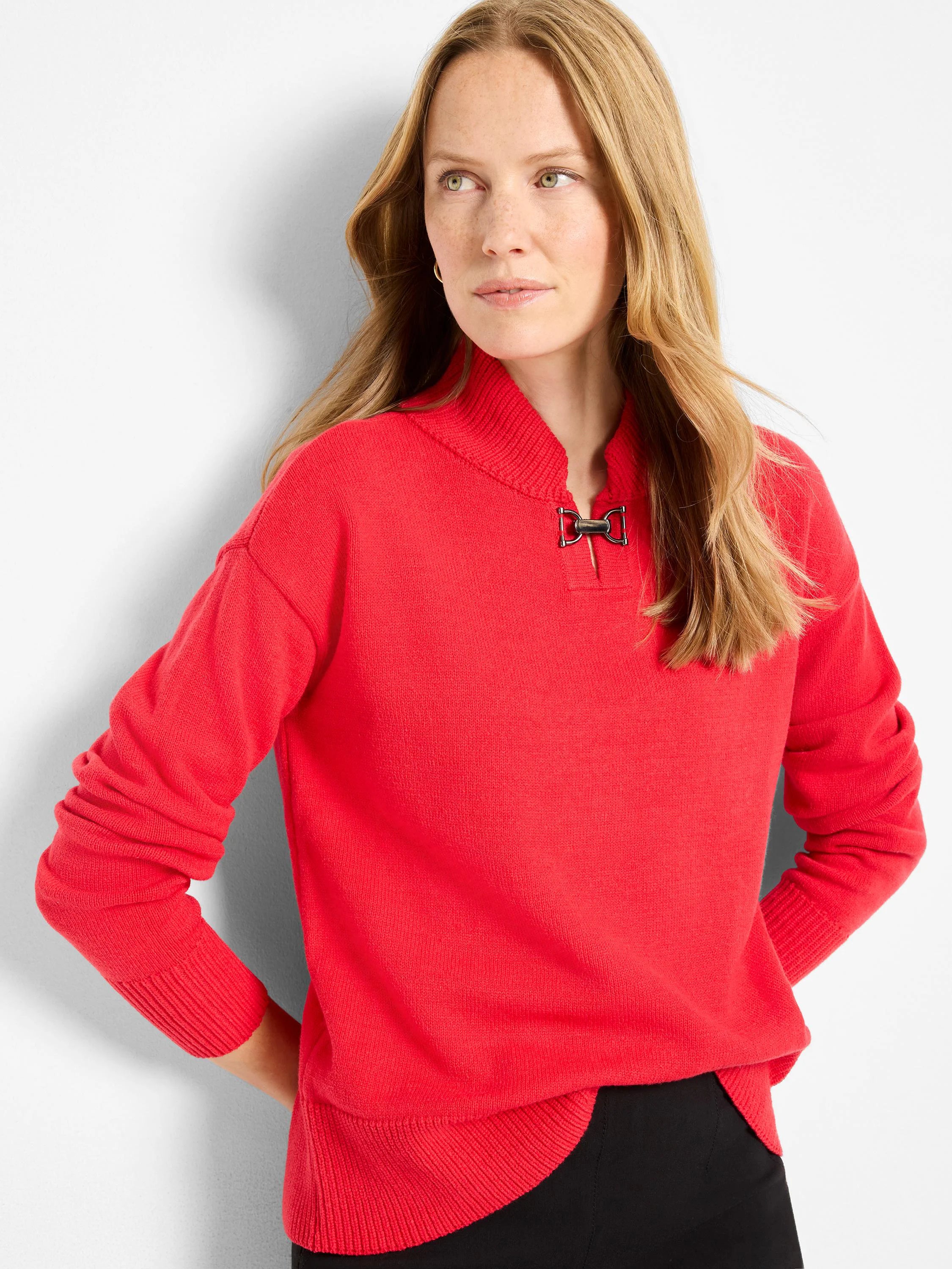 Red knit sweater with funnel neck, metal buckle closure, and curved hem.