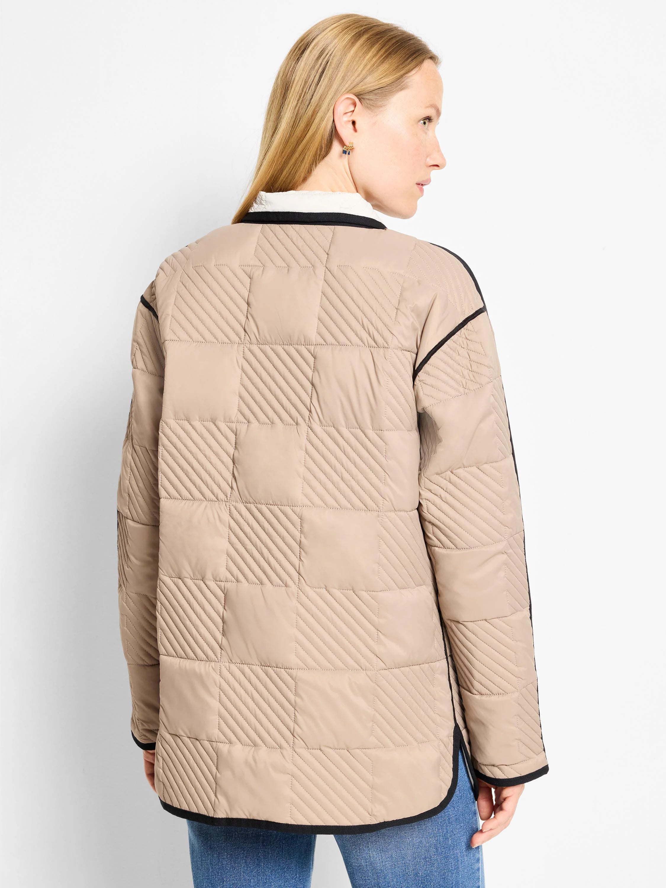 Tan barn coat with black trim. Quilted in a checkered pattern with diagonal stitching.