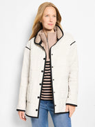 Cream quilted barn coat with subtle check pattern, black piping on edges, and snap front closure.