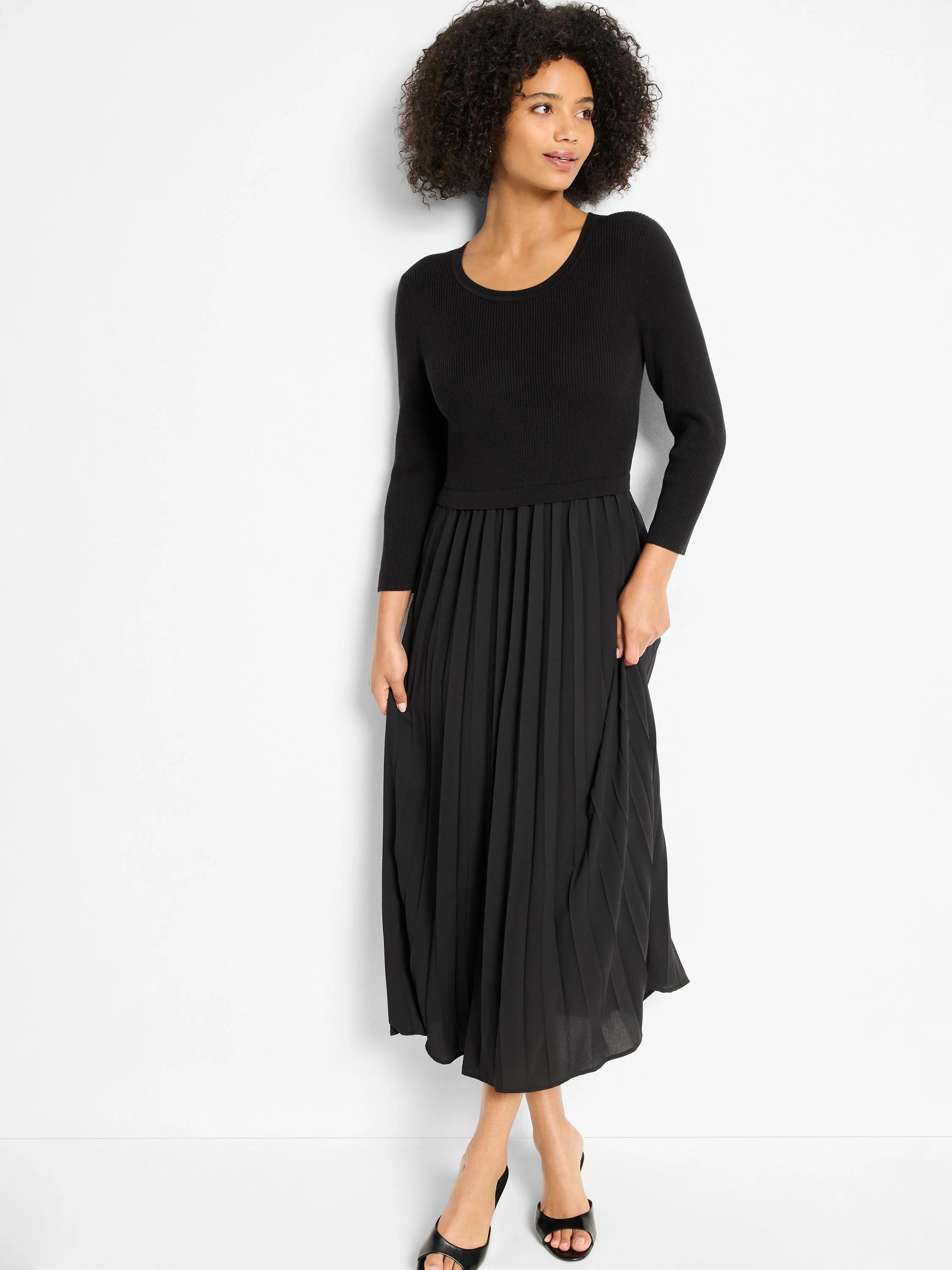 Black dress with ribbed knit bodice, long sleeves, and flowing pleated midi skirt.