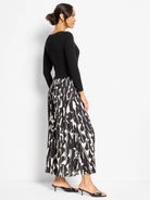 Long-sleeved black dress with a pleated maxi skirt featuring an abstract black and off-white pattern.