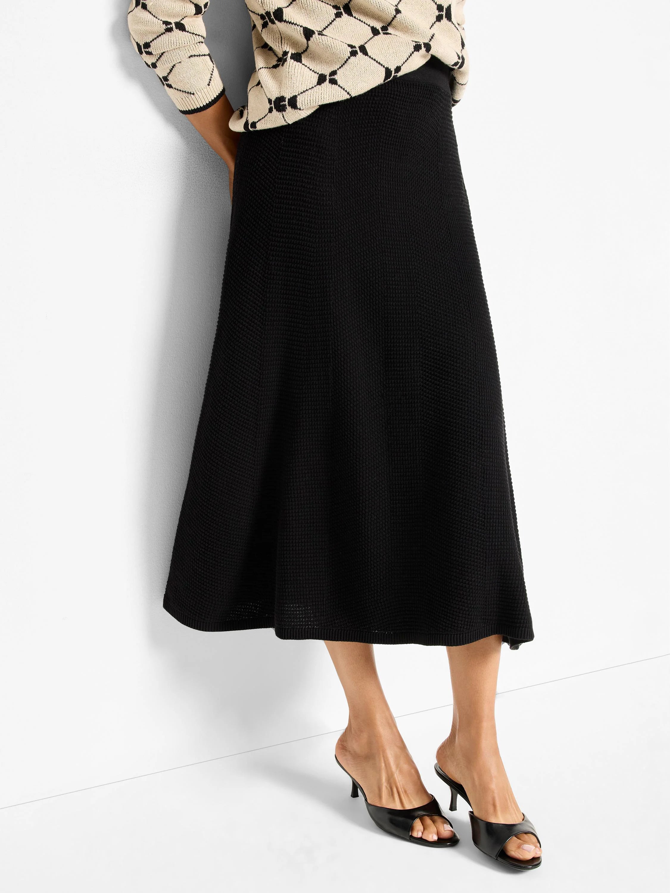 Black A-line midi skirt with a waffle-like pixel knit texture.