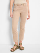 Person wearing beige pants and green sandals on a white background