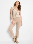 Light tan knit straight ankle jeans on a model, showing a flat waistband and a single front button.