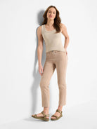 Light tan straight ankle jeans on a model. They have stitched front pockets and a single metal button closure.
