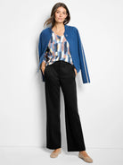 Black wide leg trousers on model, showing a smooth drape, front creases, and pockets.