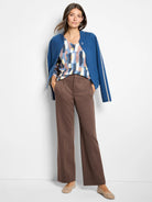 Brown, drapey wide-leg trousers with prominent front creases. Model's hands are in the side pockets.