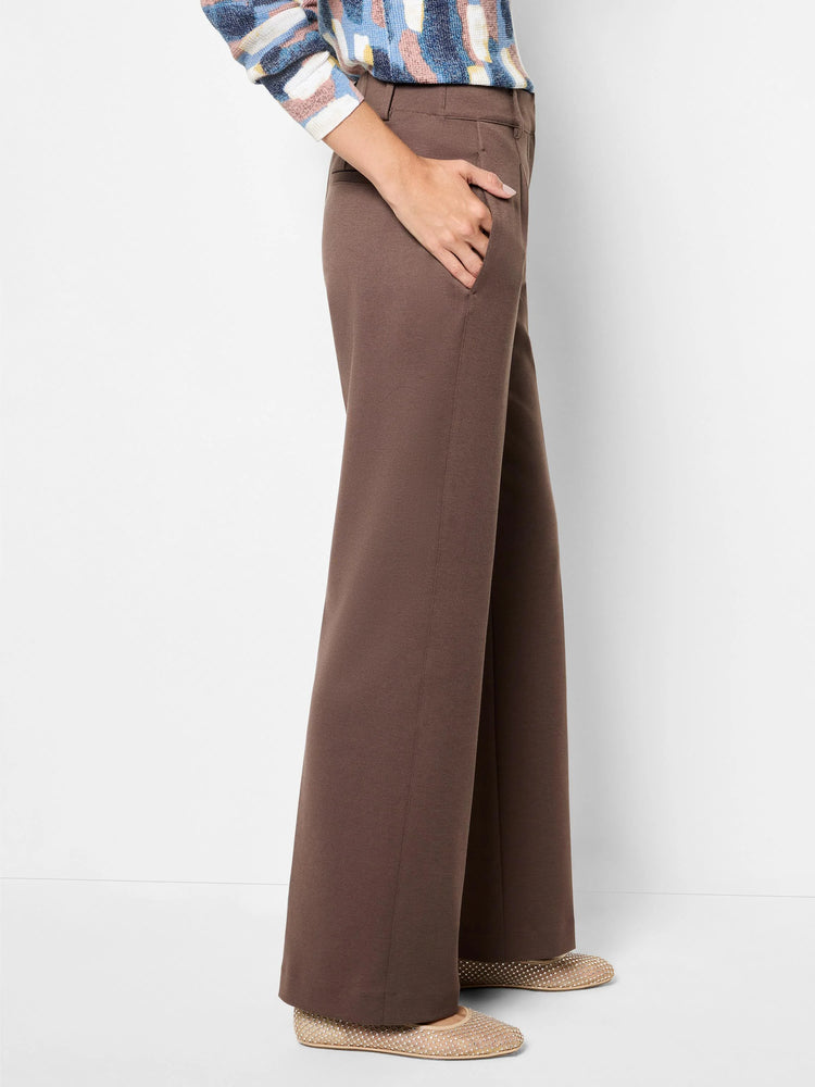 Brown drapey ponte wide-leg trousers on a model, with a hand in the pocket. Features a smooth fabric and full length.