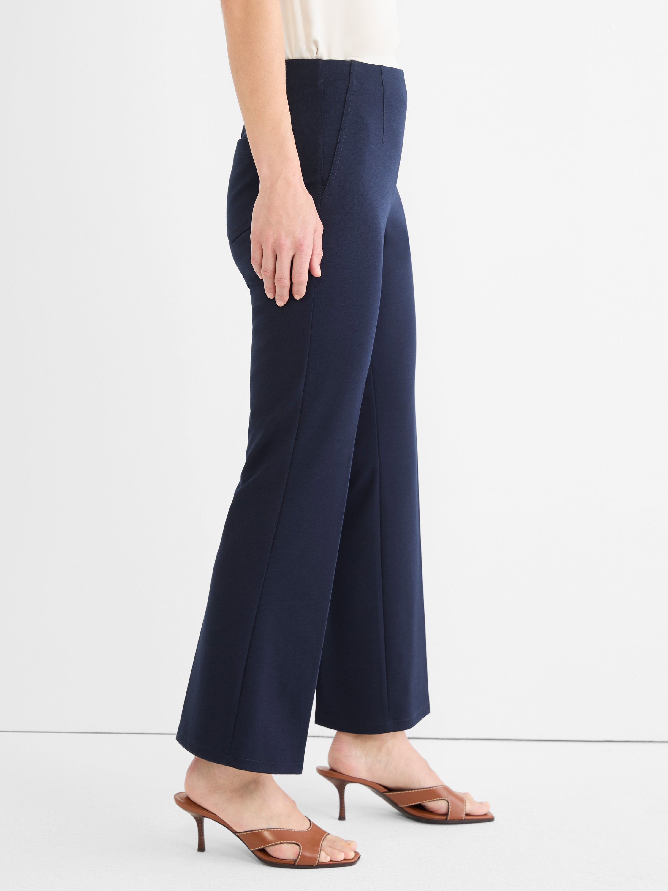 Navy high-waist trousers featuring a slim fit through the thigh, slight flare, and a cropped length.
