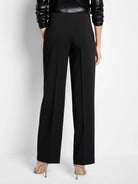 Black wide-leg pants with sharp front creases, shown from the back on a model.