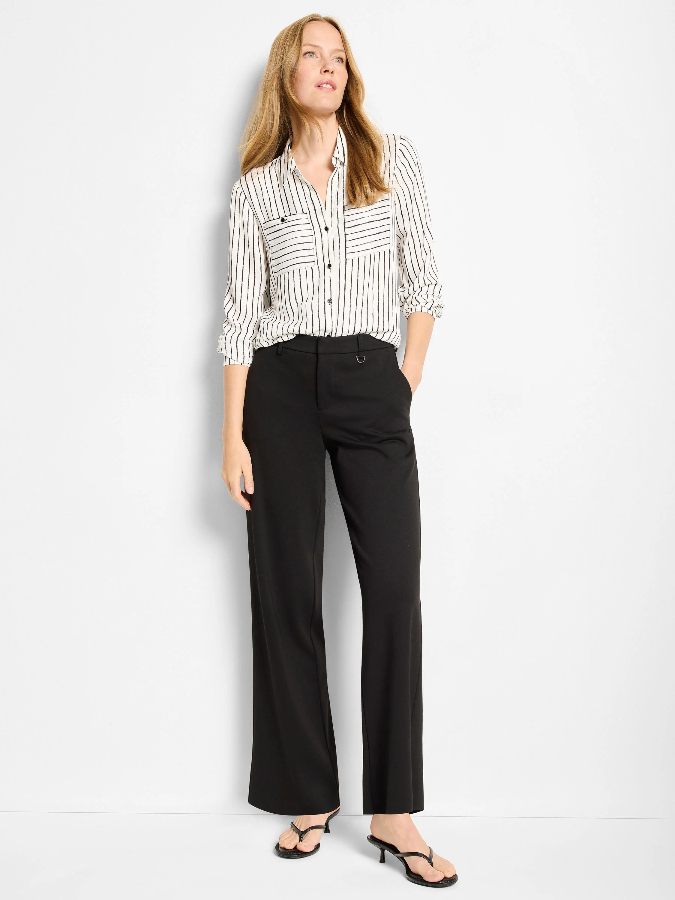 Black wide-leg pants with a small silver buckle detail at the waist.  A model is wearing them with a striped shirt.