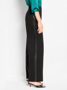 Black wide-leg tuxedo pants feature a darker, glossy stripe down the outer seam.