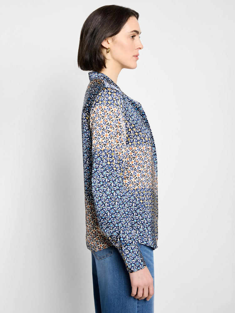 Long-sleeved button-up top with a mixed geometric pattern in blues, orange, cream, and black.