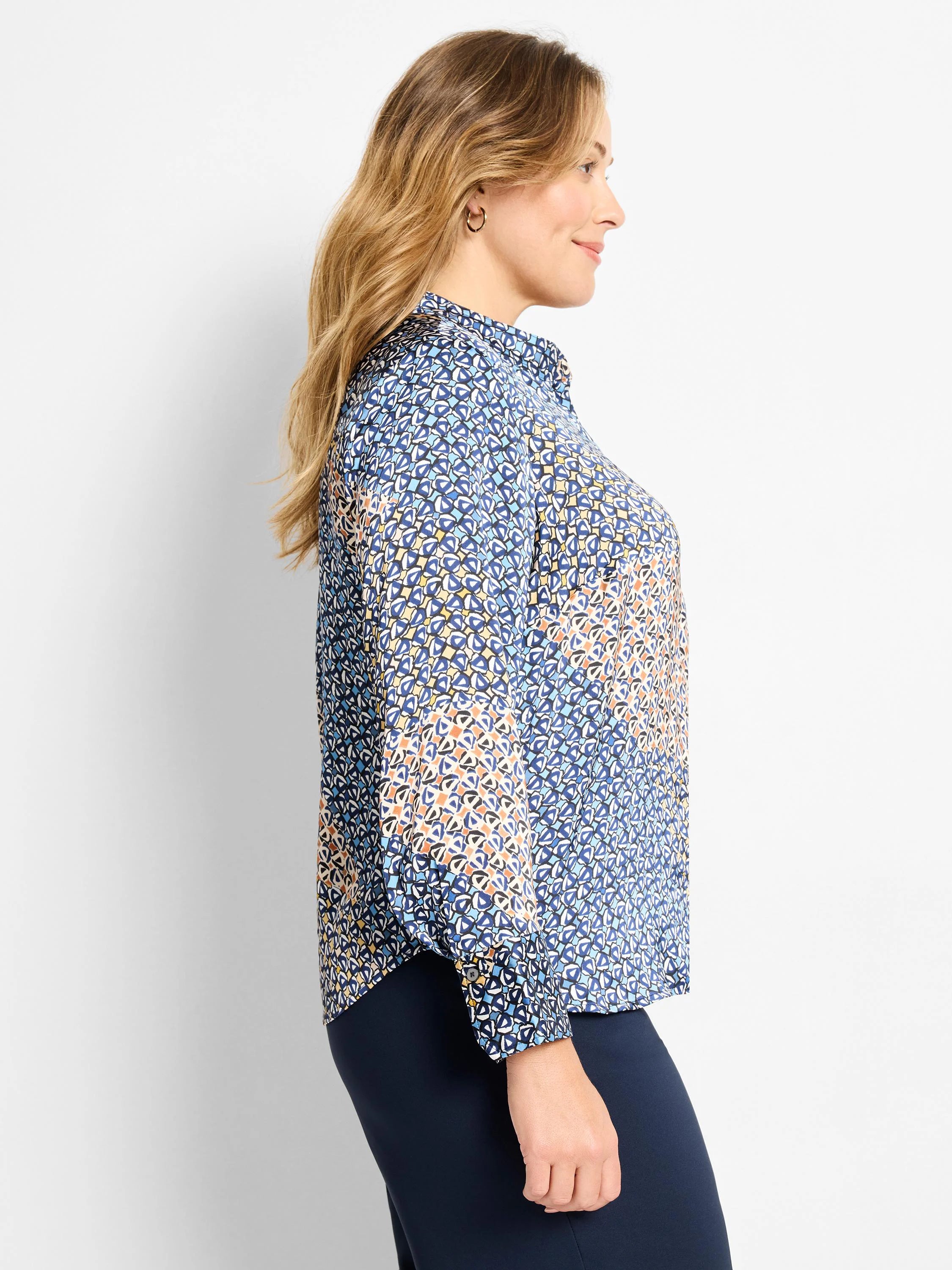 Collared long-sleeve top with a mixed monogram pattern in shades of blue, cream, and orange. Button cuffs.