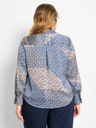 Back view of a long-sleeve top with a mixed geometric pattern in shades of blue, yellow, orange, and white.
