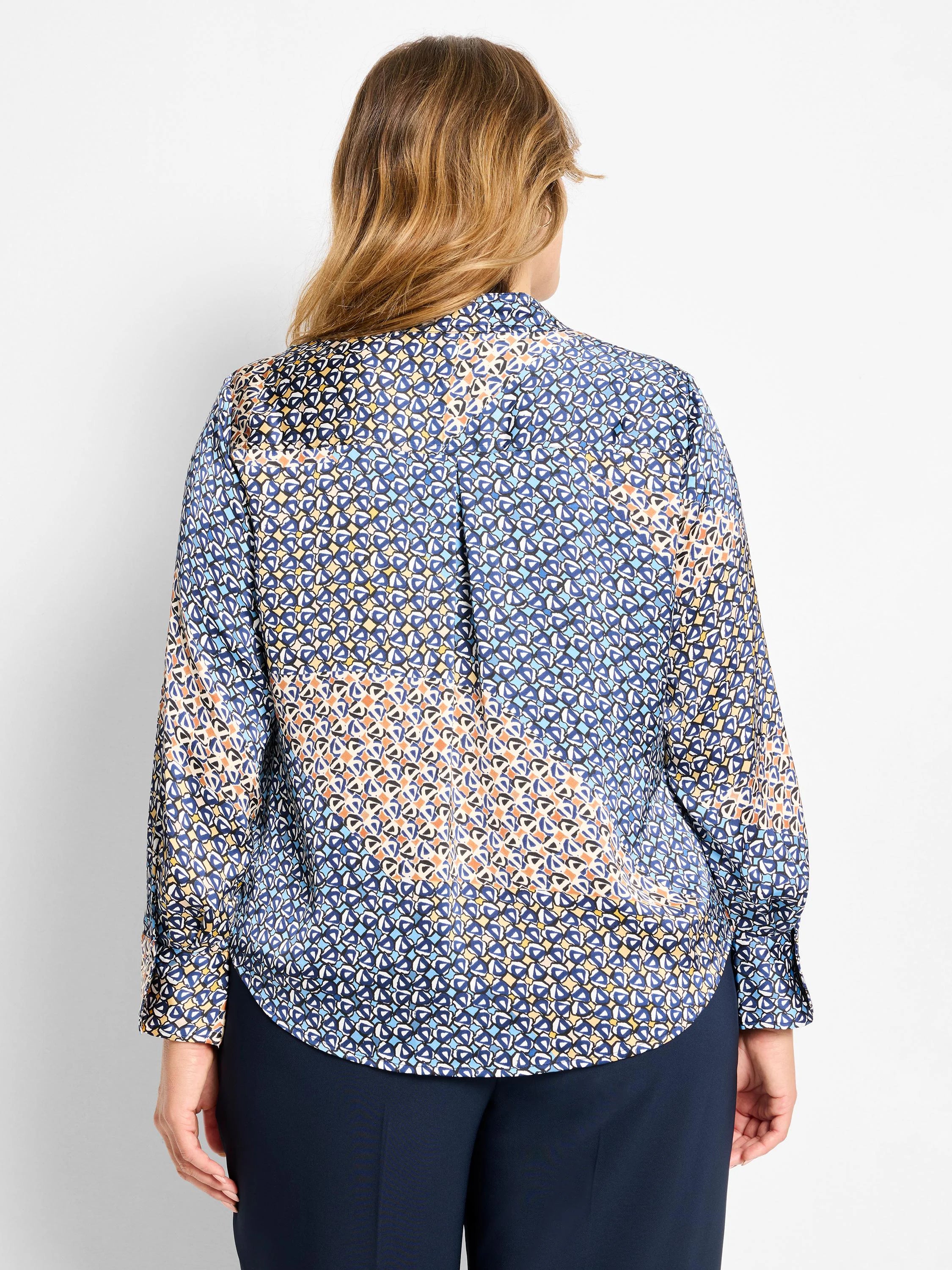 Back view of a long-sleeve top with a mixed geometric pattern in shades of blue, yellow, orange, and white.