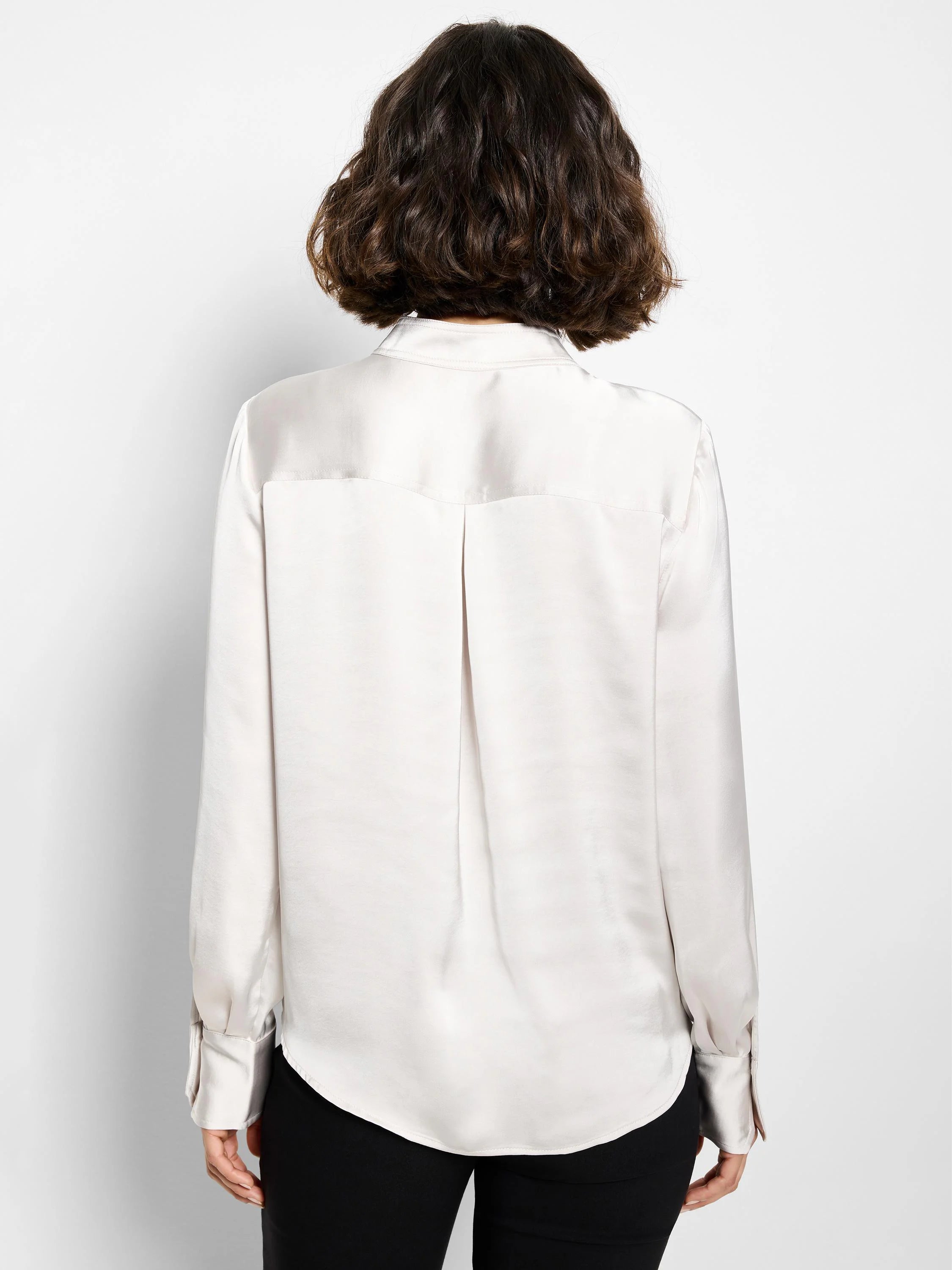 Light beige satin shirt, long sleeves with buttoned cuffs, curved hemline.  Back view.