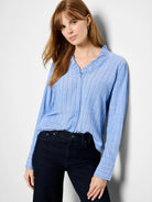 Light blue, vertically striped shirt with white stripes and ruffled neckline. Long sleeves with striped cuffs.