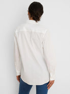 Back view of a white long-sleeved shirt with buttoned cuffs, a back yoke, and a locker loop.