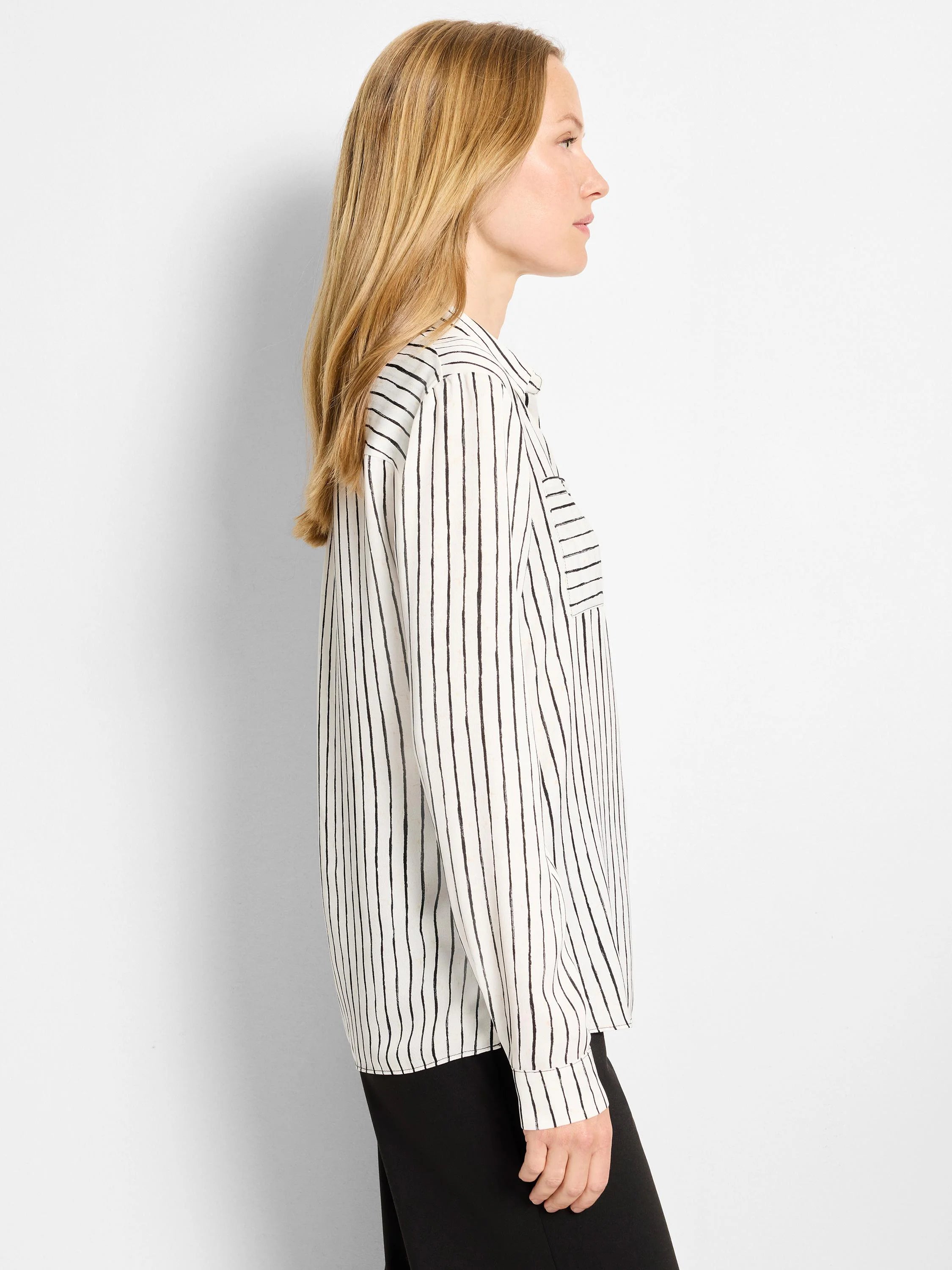 White shirt with vertical black brushstroke stripes. Features a chest pocket with horizontal stripes and long sleeves.