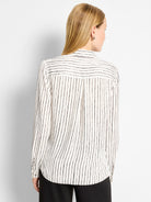 White shirt with thin, painted-look black stripes. Vertical on body, horizontal on back yoke. Long sleeves.