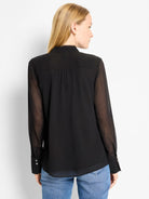 Black chiffon top with opaque body, sheer long sleeves, stand collar, pleated back, and two-button cuffs.