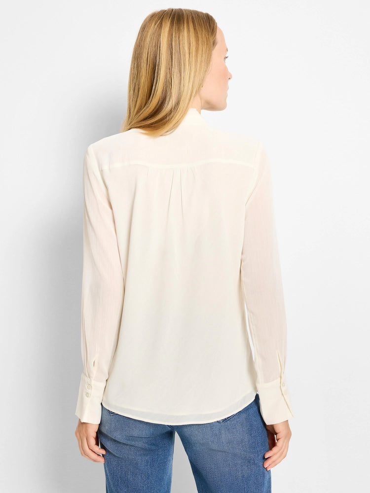Cream sheer chiffon top, back view. Features pleated back yoke, long sleeves with buttoned cuffs, and a curved hem.