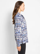 Long-sleeved top with an abstract blue, black, cream, and tan dot pattern.