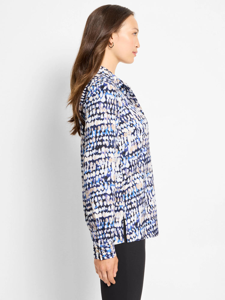 Long-sleeved top with an abstract blue, black, cream, and tan dot pattern.