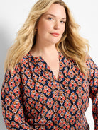 V-neck top with an ikat pattern of orange, red, brown, and blue outlined diamond shapes on a dark ground.