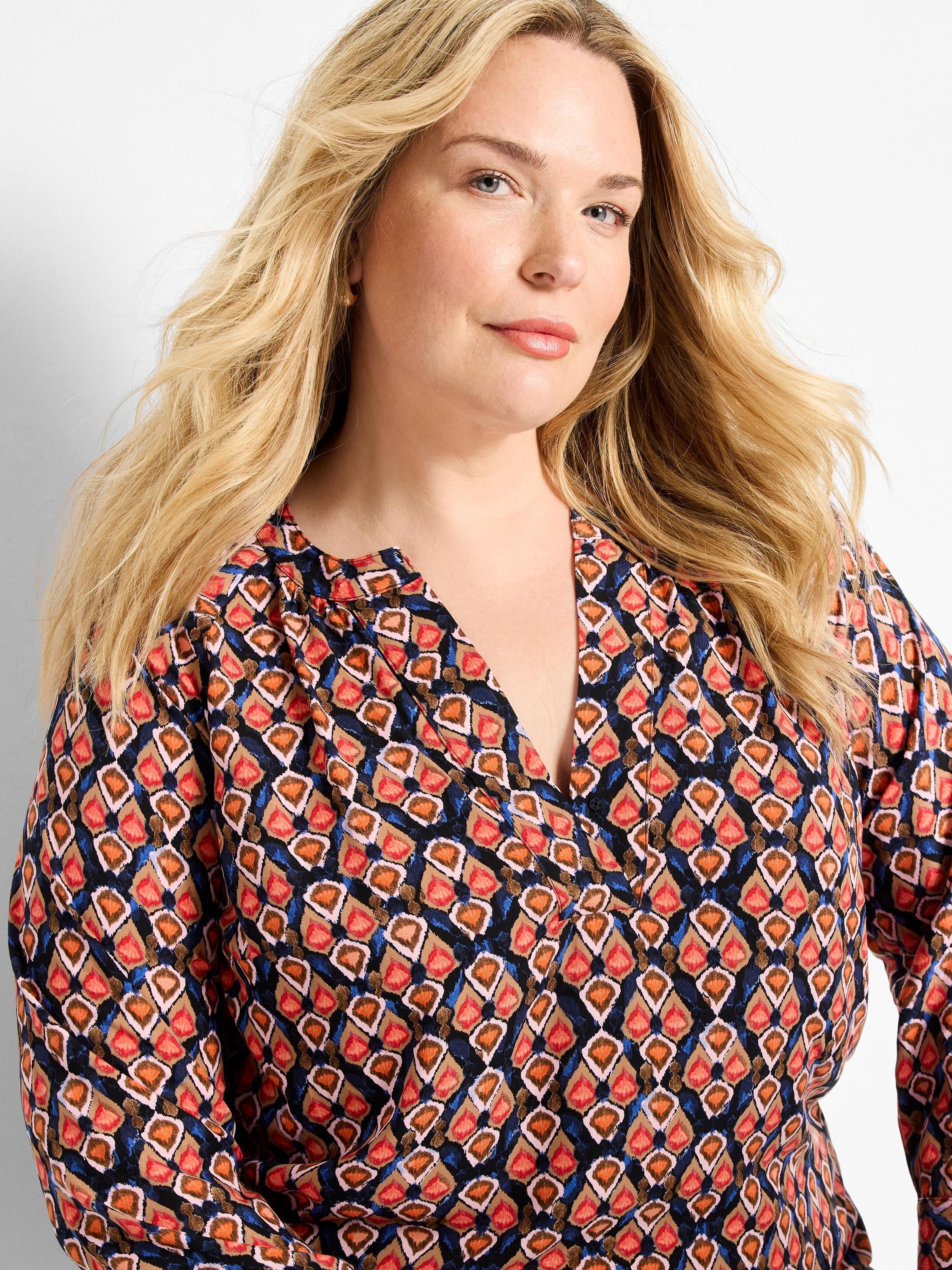 V-neck top with an ikat pattern of orange, red, brown, and blue outlined diamond shapes on a dark ground.