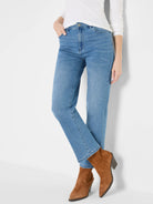 Medium blue straight ankle jeans, worn. Features button closure, front pockets, and a clean hem above brown boots.