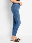 Medium blue denim straight ankle jeans, side view. Visible front pockets, belt loops, and subtle texture variation.