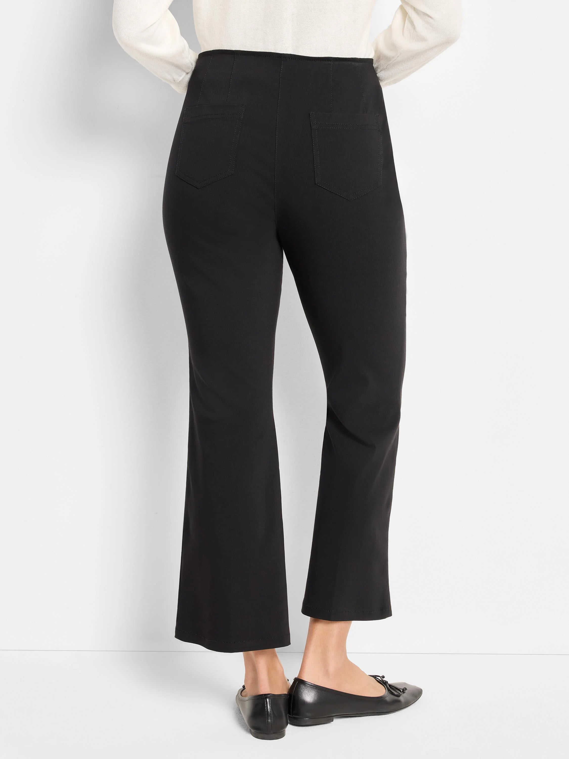 Black cropped bootcut pants. They feature a smooth waist, vertical back seams, and two stitched patch pockets.