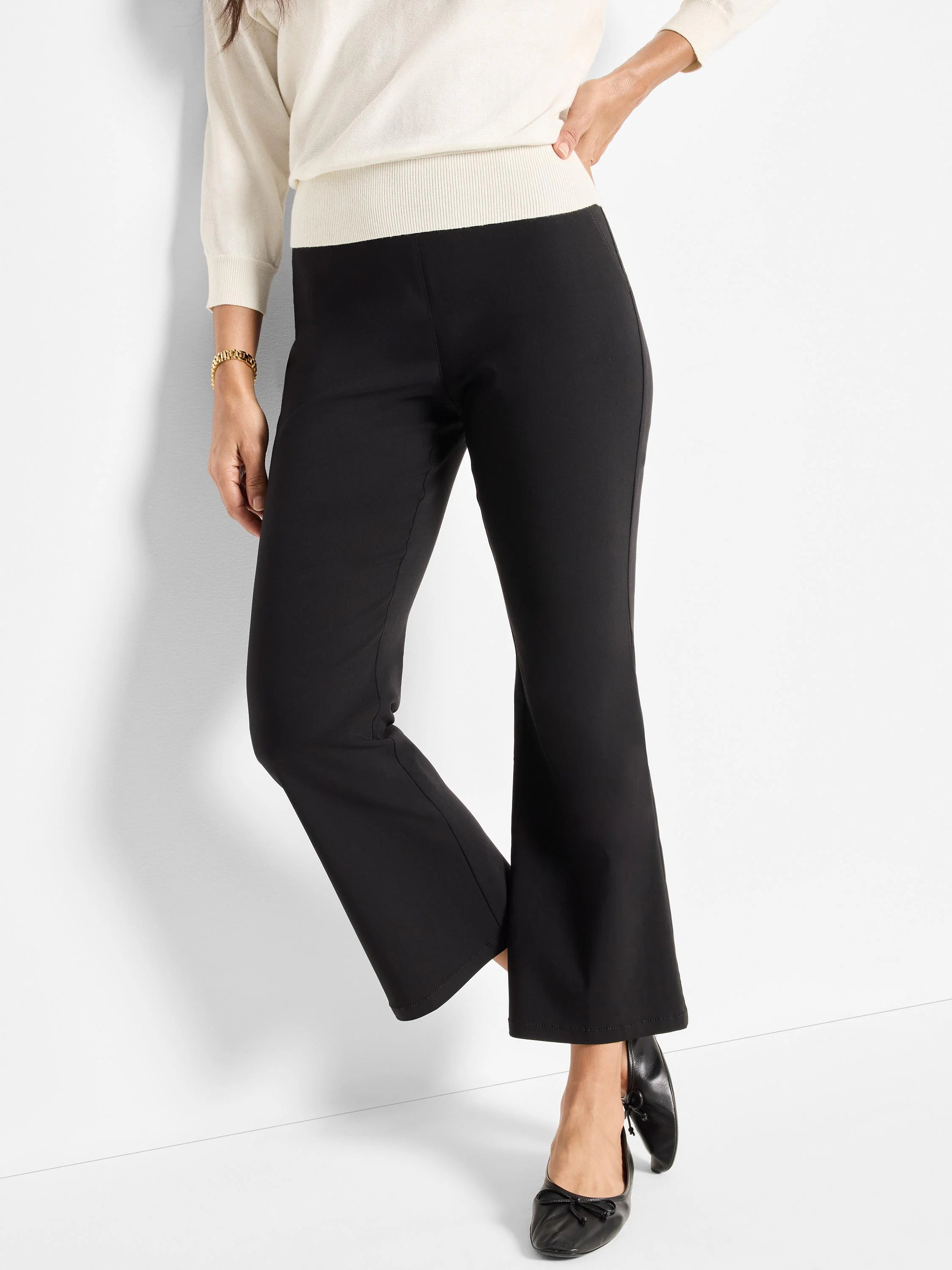 Black bootcut pants with a flat, smooth waistband. Full-length legs gently flare at the hem.