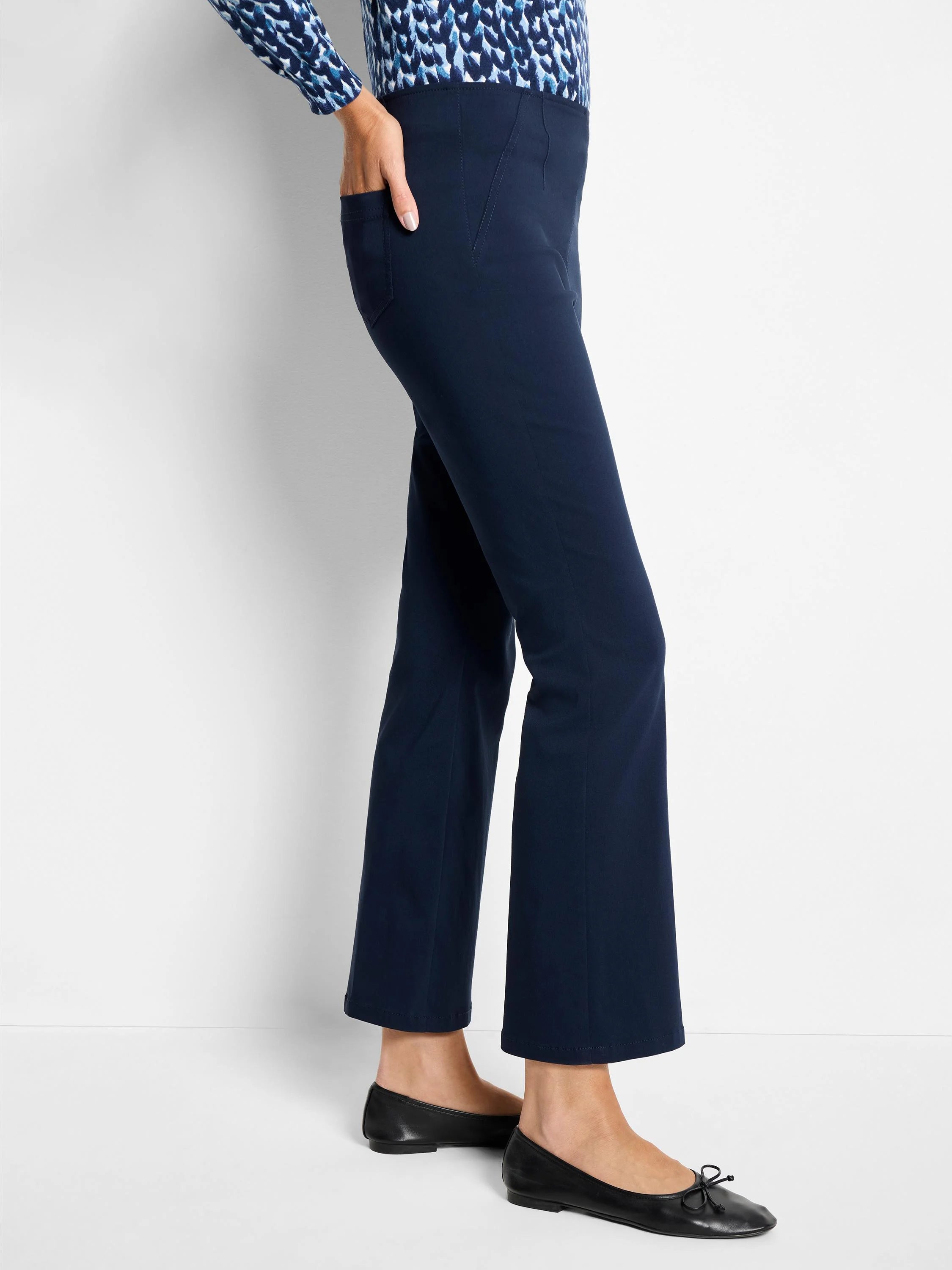 Navy blue bootcut pants with subtle vertical seam details and a side pocket, modeled from the side.