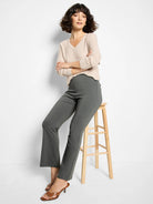 Deep olive bootcut pants, fitted through the hip and thigh, with a subtle flare. Model is seated.