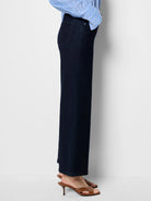 Dark indigo boot flare jeans on a model, with a classic back pocket and legs widening from knee to hem.
