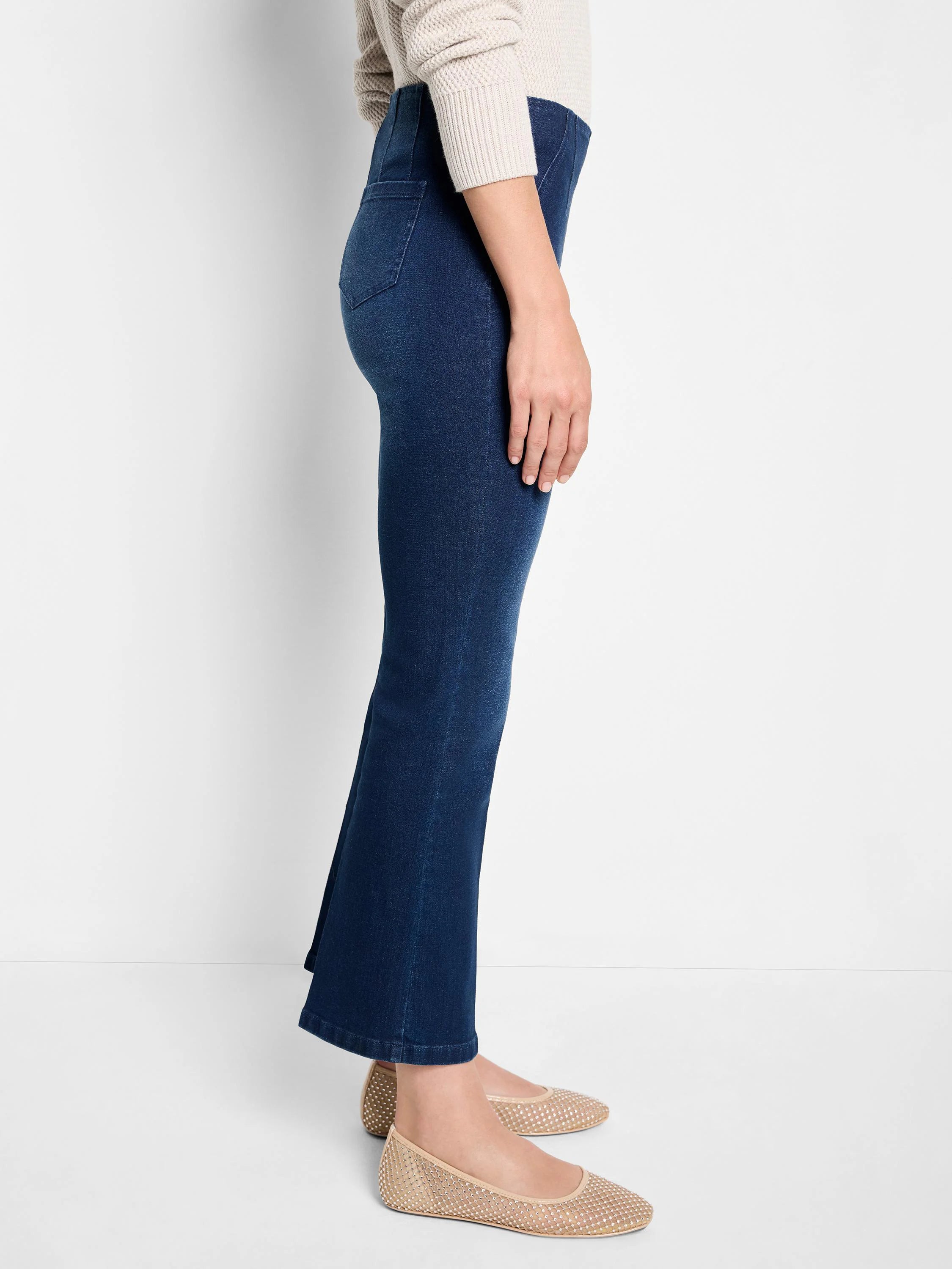 Dark wash boot-cut jeans shown on a model.  Jeans are dark blue;  model wears beige shoes.