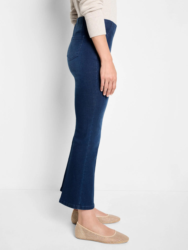 Dark wash boot-cut jeans shown on a model.  Jeans are dark blue;  model wears beige shoes.
