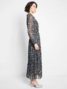 Black maxi dress with sheer long sleeves, ruffled neck, and abstract blue, tan, white pattern. Tiered skirt, elastic waist.