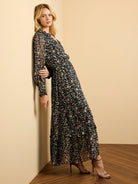Black maxi dress with beige, blue, brown abstract cheetah print. V-neck, long sleeves, cinched waist, flowing skirt.